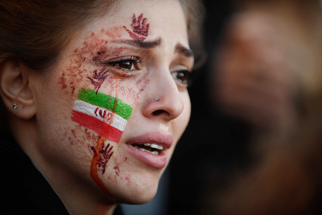 PARIS: A demonstrator with an Iranian flag and red hands painted on her face attends a rally on Oct 9, 2022, following the death of Iranian woman Mahsa Amini in Iran. - AFP