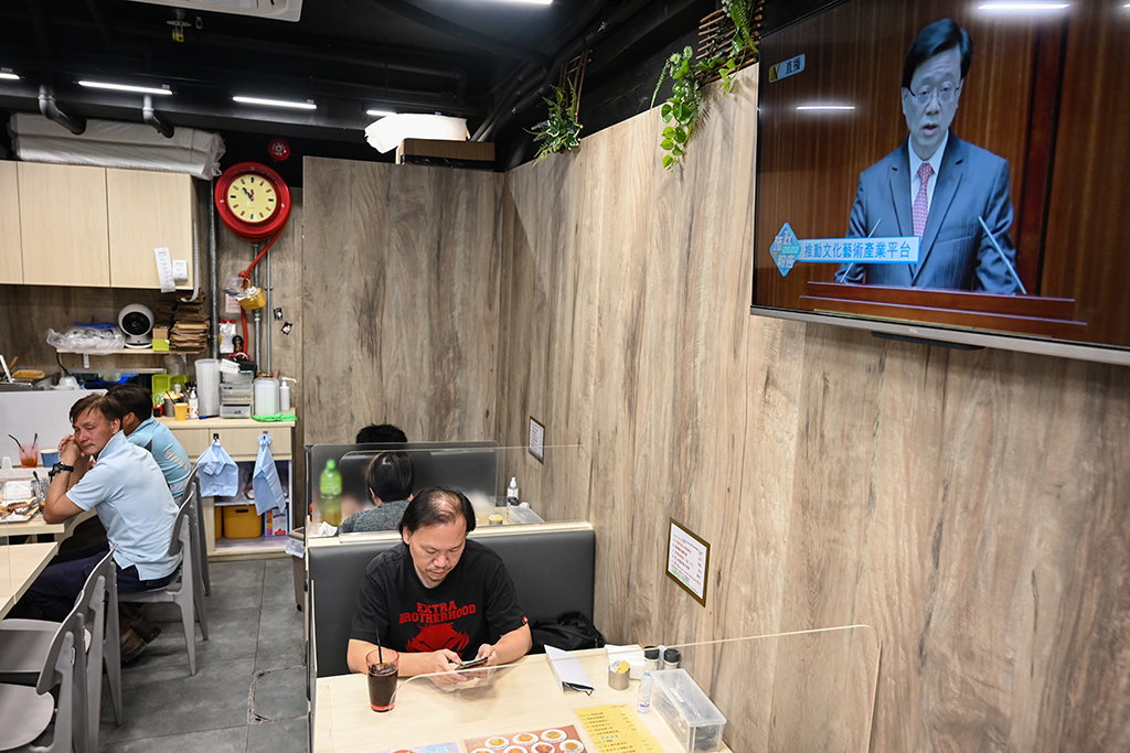 HONG KONG, China: Diners have lunch as Hong Kong's Chief Executive John Lee is seen on a tv delivering his first policy address in Hong Kong on October 19, 2022. – AFP