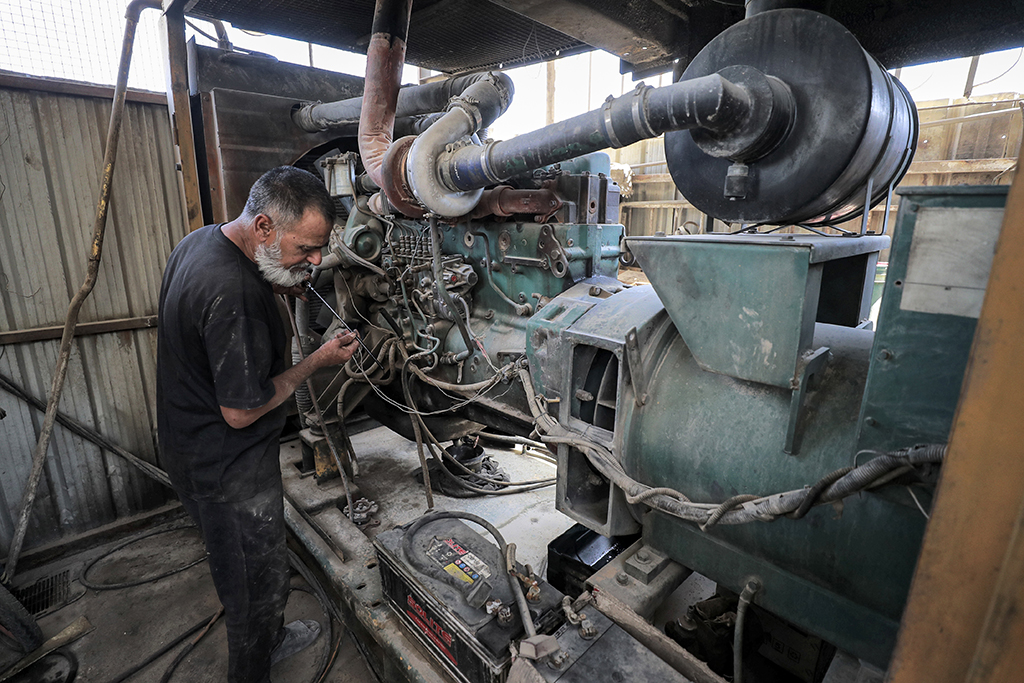 SADR CITY, Iraq: A technician checks the oil on the dipstick of one of the fuel-based electricity generators in a battery in the eastern Sadr City suburb of Iraq's capital Baghdad.— AFP
