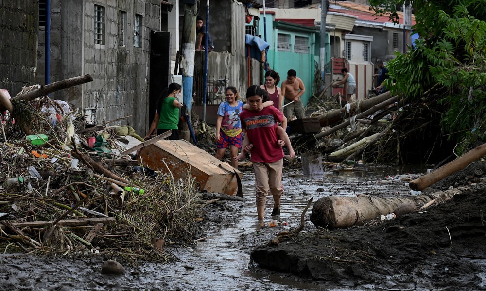 People walk along a mud-covered street in Noveleta, Cavite province on October 30, 2022, a day after Tropical Storm Nalgae hit.