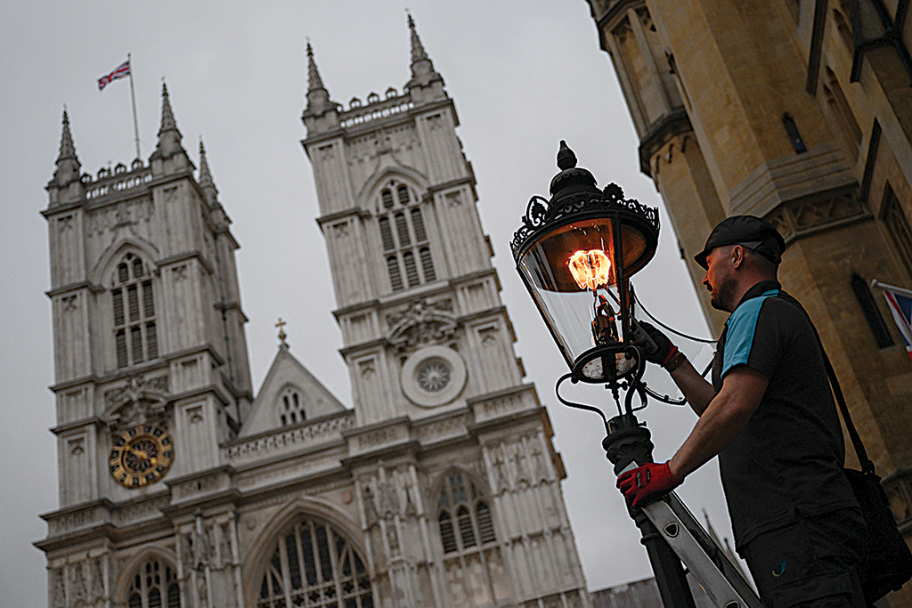 A British Gas engineer services a gas-powered lamp near Westminster Abbey in central London.— AFP photos
