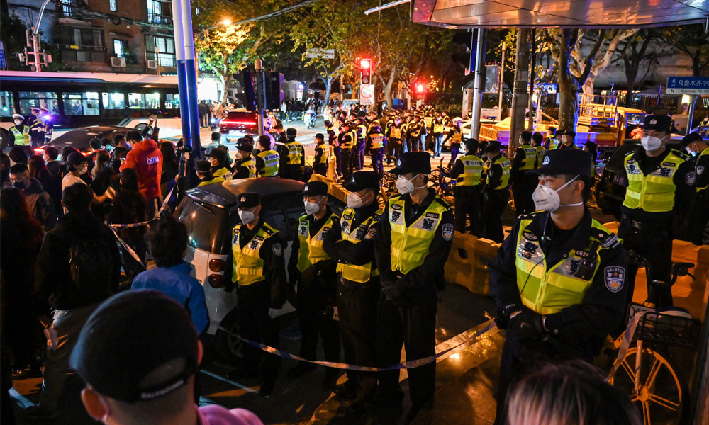 Police officers block Wulumuqi street, named for Urumqi in Mandarin, in Shanghai on November 27, 2022,