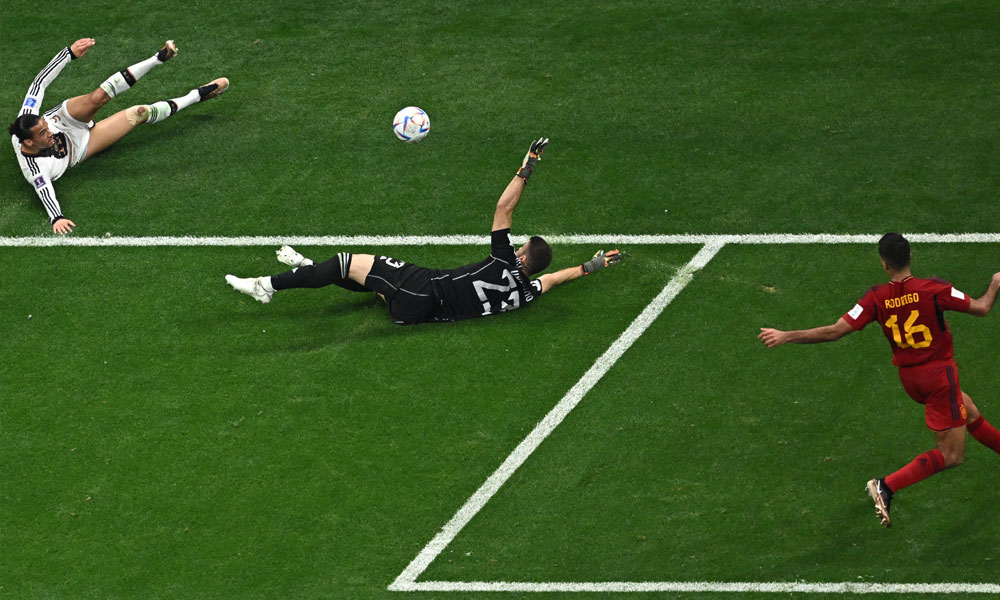 Spain's goalkeeper #23 Unai Simon dives for the ball after a shot by Germany's forward #19 Leroy Sane during the Qatar 2022 World Cup