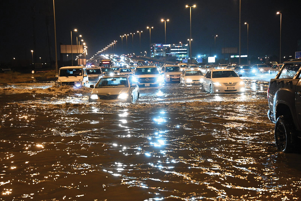 KUWAIT: Motorists traverse through a flooded road following heavy rains on Friday. - Photo by Yasser Al-Zayyat