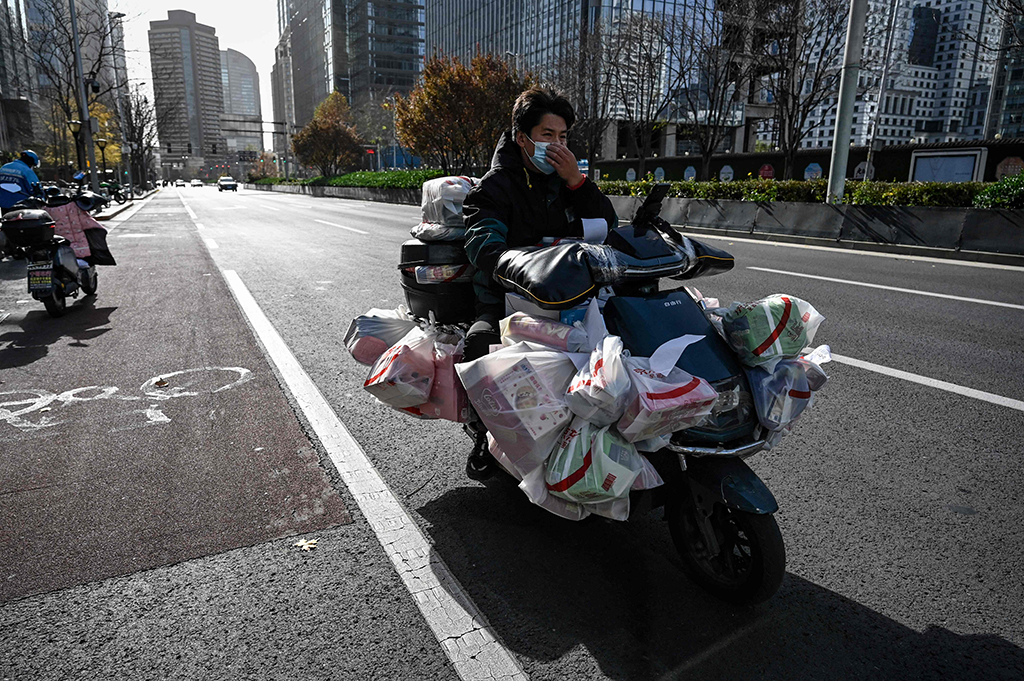 BEIJING: A food delivery man rides a scooter full of orders along a street on Nov 25, 2022. – AFP