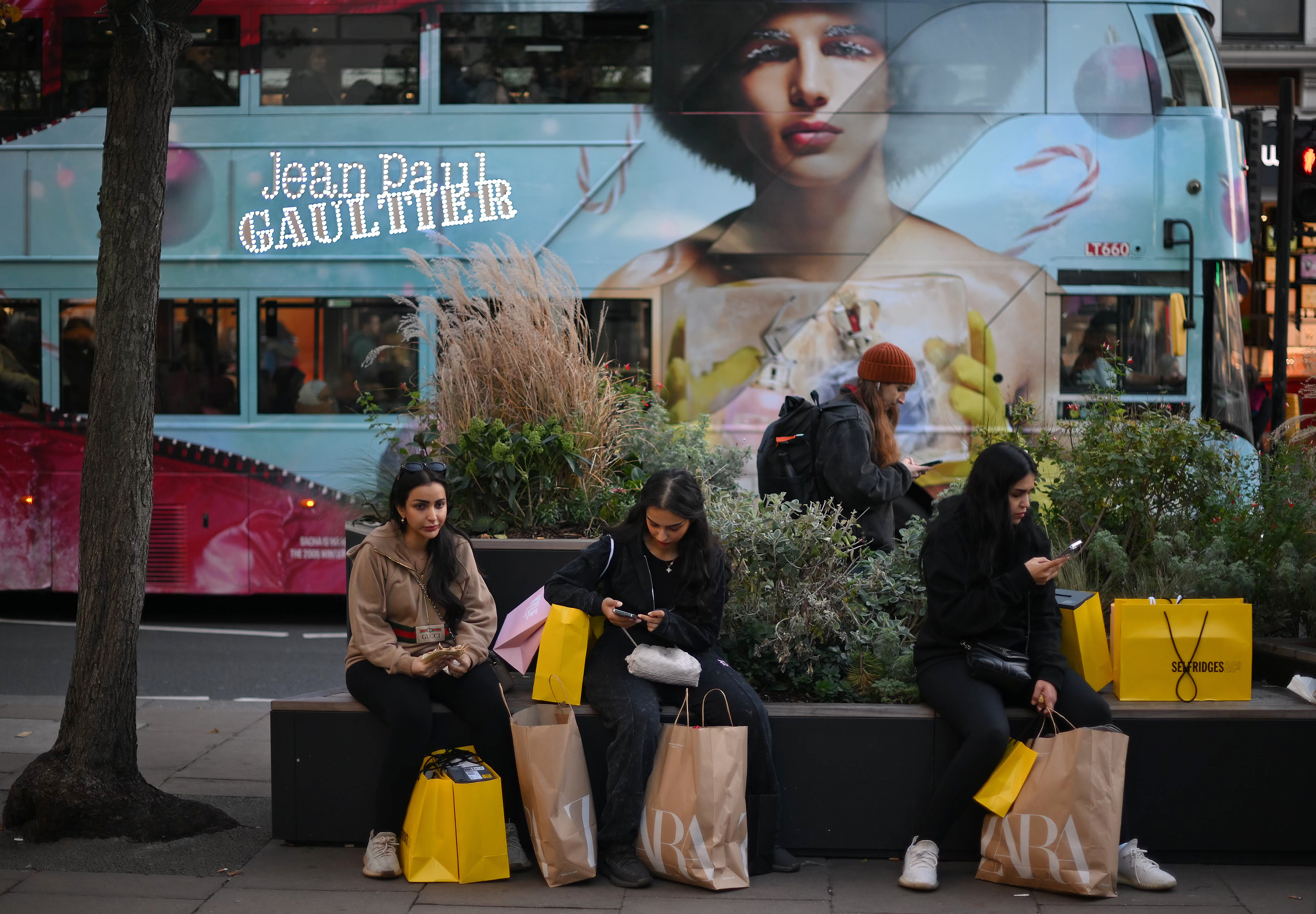 Shoppers sit with their purchases in Selfridges and Zara-branded shopping bags on Black Friday in central London on November 25, 2022. (Photo by Daniel LEAL / AFP)
