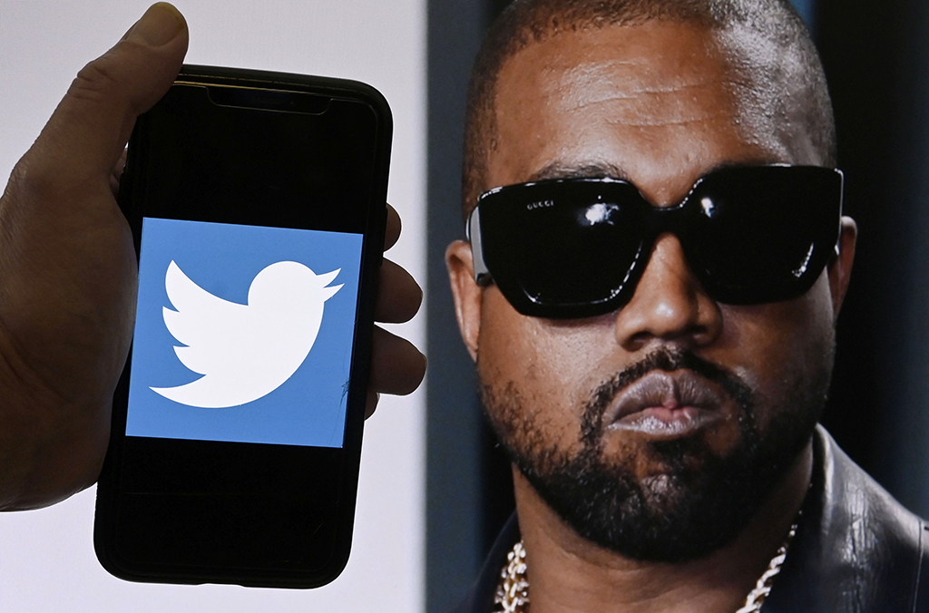 In this file photo illustration, the Twitter logo is displayed on a mobile phone with a photo of Kanye West shown in the background.— AFP