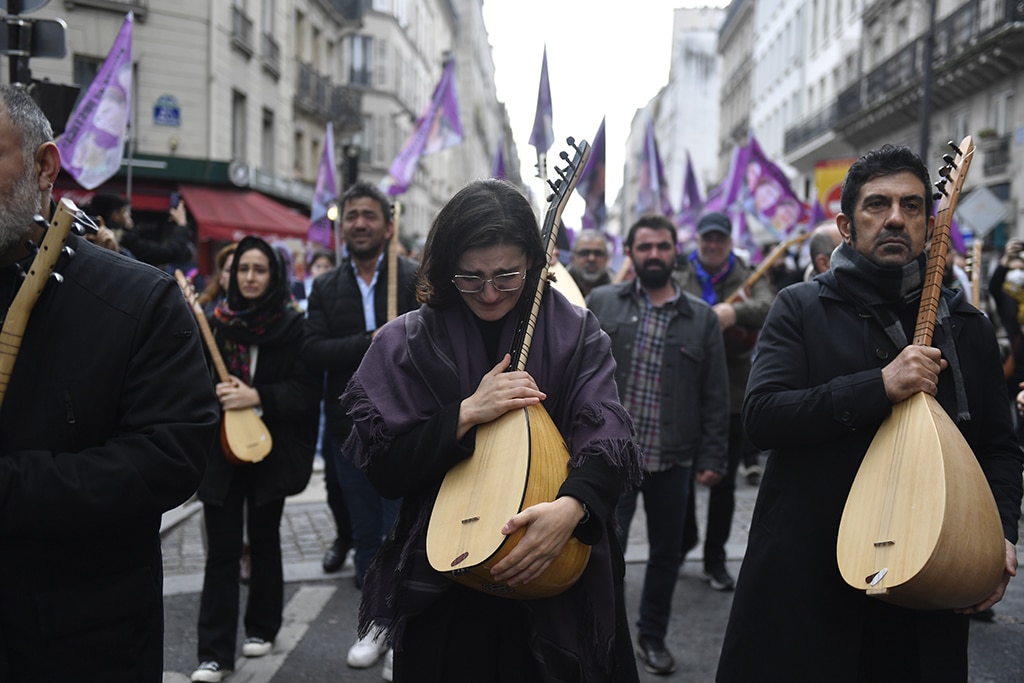 PARIS: Protesters react as they hold Kurdish traditional musical instruments while taking part in a demonstration to pay tribute to the Enghien Street shooting victims in Paris. - AFP