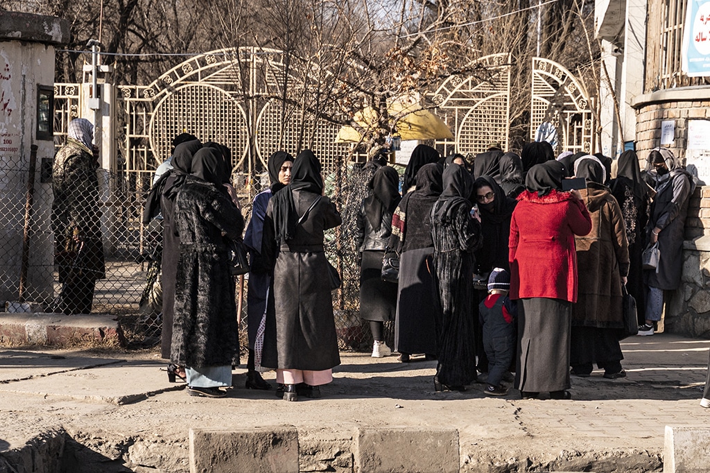 KABUL: Afghan female university students stop by Taleban security personnel stand next to a university in Kabul on December 21, 2022. – AFP