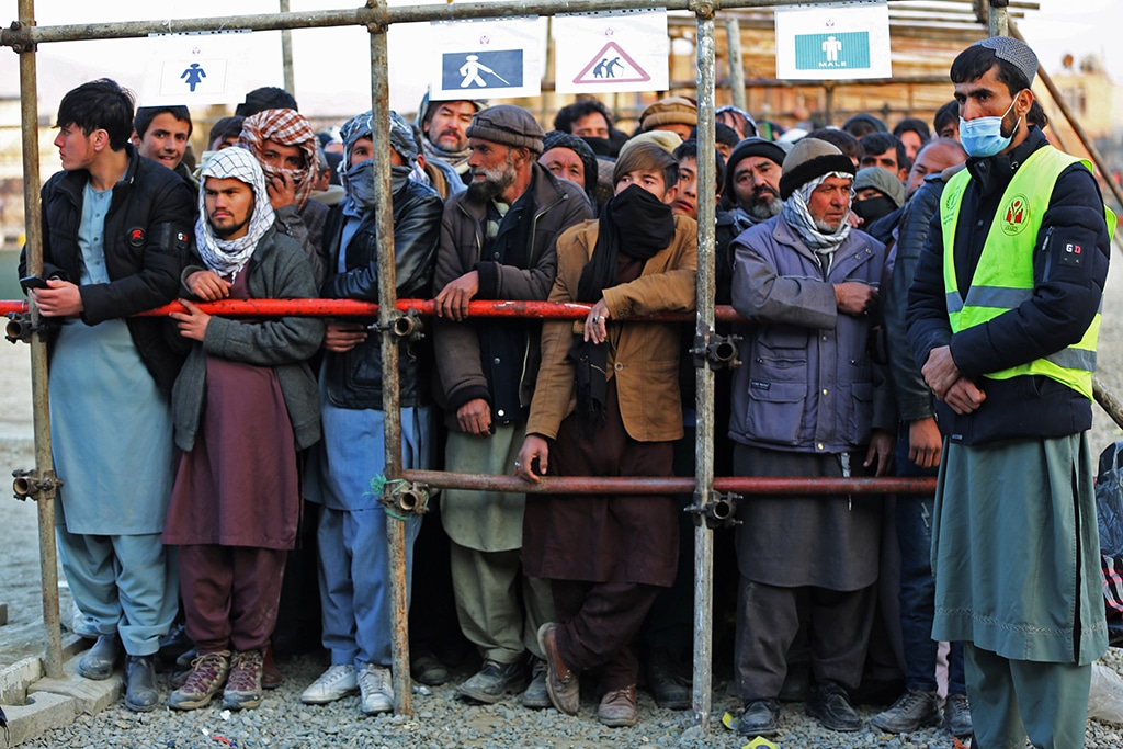 KABUL; Afghan men stand in queues to receive food aid from a non-governmental organisation (NGO) in Kabul. Several foreign aid groups announced they were suspending their operations in Afghanistan after the country's Taleban rulers ordered all NGOs to stop women staff from working. - AFP