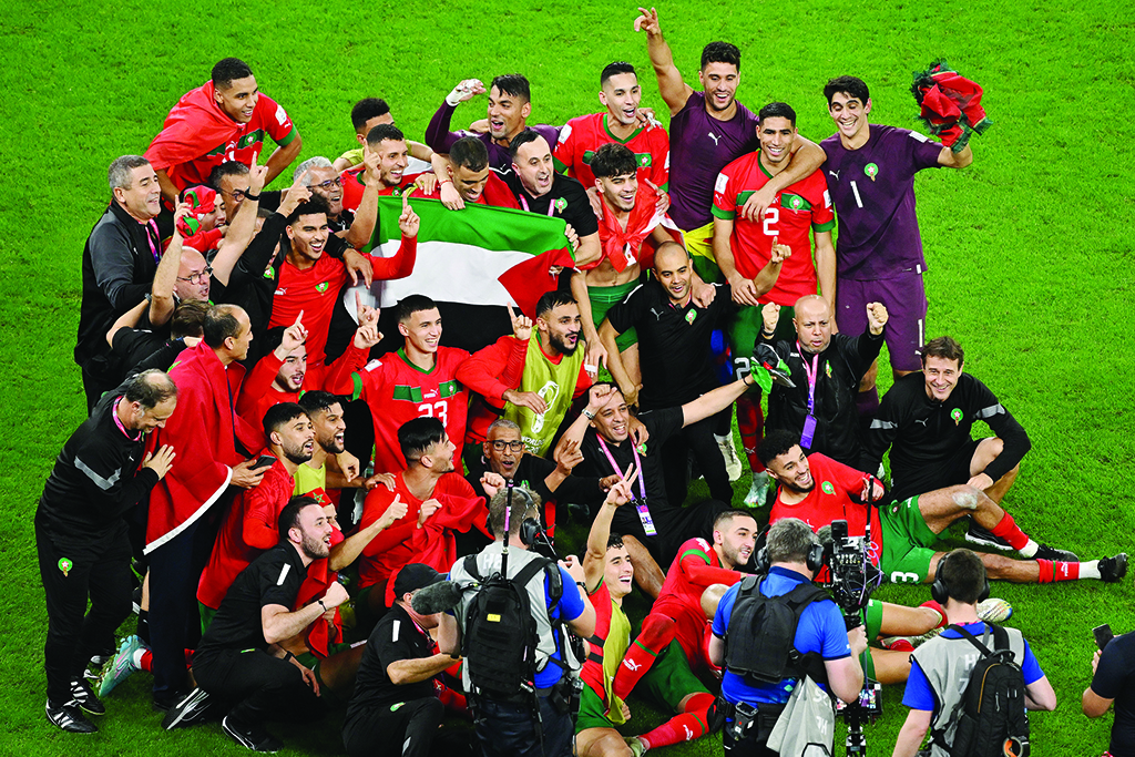 DOHA: Morocco's players celebrate with a Palestinian flag at the end of the Qatar 2022 World Cup round of 16 football match against Spain at the Education City Stadium in Al-Rayyan on Dec 6, 2022. - AFP