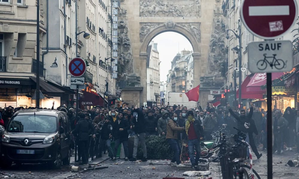 Protestors stand in front of riot police officers following a statement by French Interior Minister Gerald Darmanin, in Paris on December 23, 2022.