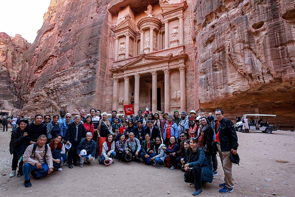 Tourists in a group pose for a photo before the site of the Treasury at the ruins of the ancient Nabatean city of Petra in southern Jordan.— AFP photos