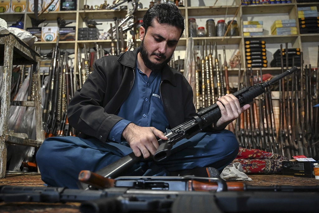 An arms dealer Muhammad Jahanzeb checks an automatic gun at his shop in Darra Adamkhel town.