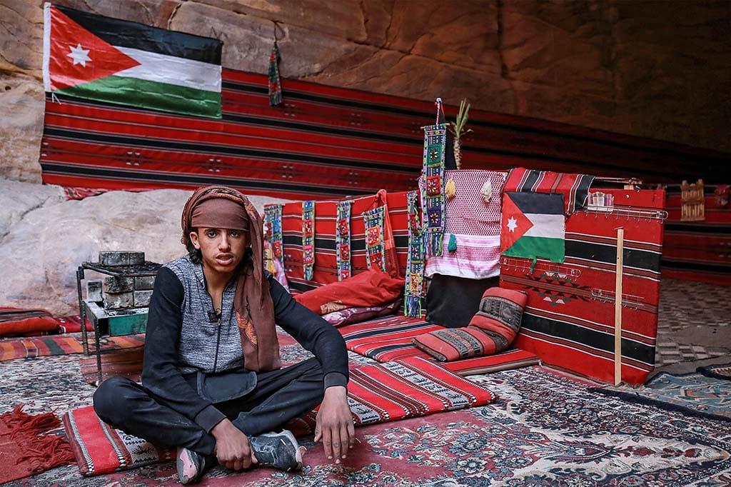 Mohammad Samahin, a 16-year-old who serves traditional coffee and tea for tourists while resting on traditional 