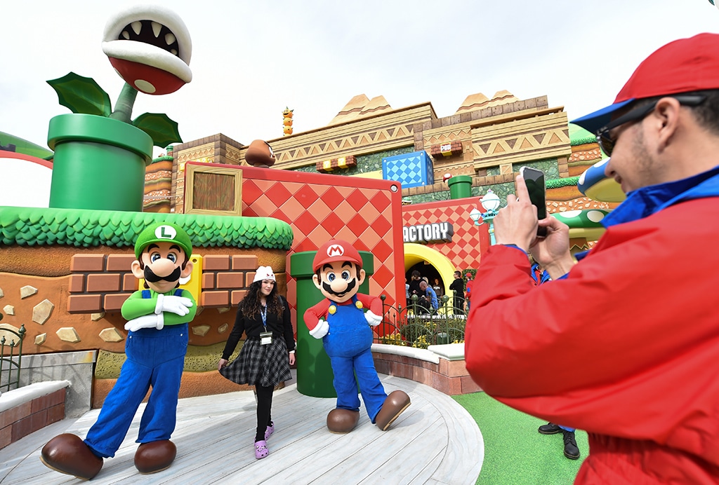 An employee takes pictures of guests with Mario and Luigi during a preview of Super Nintendo World at Universal Studios in Los Angeles, California.- AFP photos