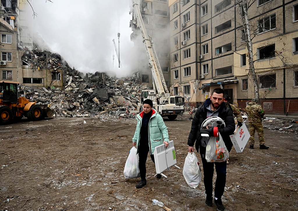 DNIPRO: Residents carry their belongings from a residential building destroyed after a missile strike, in Dnipro on January 15, 2023, amid the Russian invasion of Ukraine. - AFP