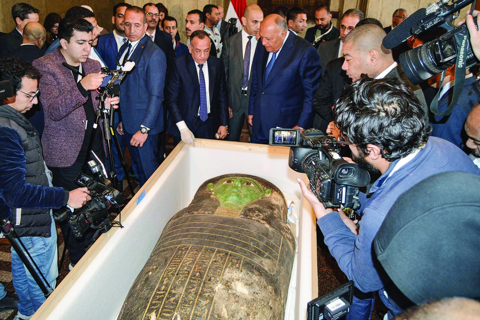 Egypt's Foreign Minister Sameh Shoukry (C-R) and the head of the Supreme Council of Antiquities Mostafa Waziri (C-L) are surrounded by journalists as they inspect an ancient Egyptian wooden sarcophagus being handed over and which was formerly displayed at Houston Museum of Natural Sciences after having been looted and smuggled years prior, at the foreign ministry headquarters in the capital Cairo on January 2, 2023. (Photo by AFP)