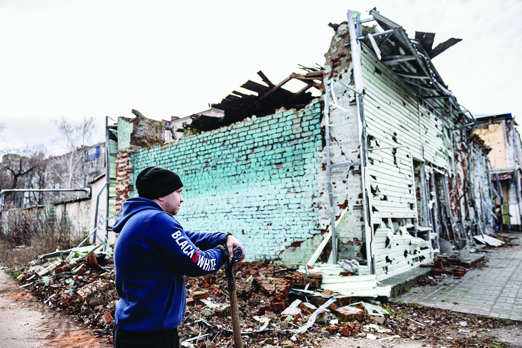 A local resident stands as he removes debris near his damaged house in the city of Izium, eastern Ukraine on January 2, 2023. (Photo by Sameer Al-DOUMY / AFP)