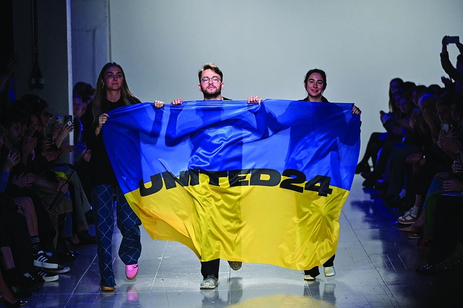 (From left) Ukrainian fashion designers Ksenia Schnaider, Ivan Frolov and Julie Paskal wave a Ukraine’s flag as they walk down the catwalk prior to the Autumn/Winter 2023 Ukrainian fashion show collection on the fifth day of the London Fashion Week, in London.— AFP