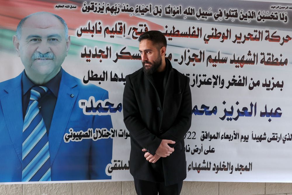 NABLUS: Palestinian nurse Elias al-Ashqar stands by a billboard bearing an obituary for his father Abdel Aziz, on February 24, 2023, who died during a Zionist raid in Nablus in the occupied West Bank two days earlier. - AFP