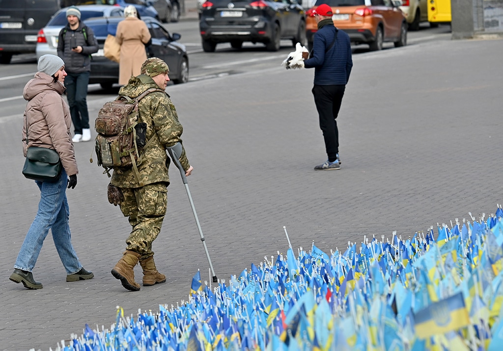 KYIV: A wounded Ukrainian serviceman and his girlfriend walk past national flags each of which symbolizing the dead serviceman set at Independence Square in Kyiv on February 22, 2023, two days before the first anniversary of the Russian invasion to Ukraine. - AFP