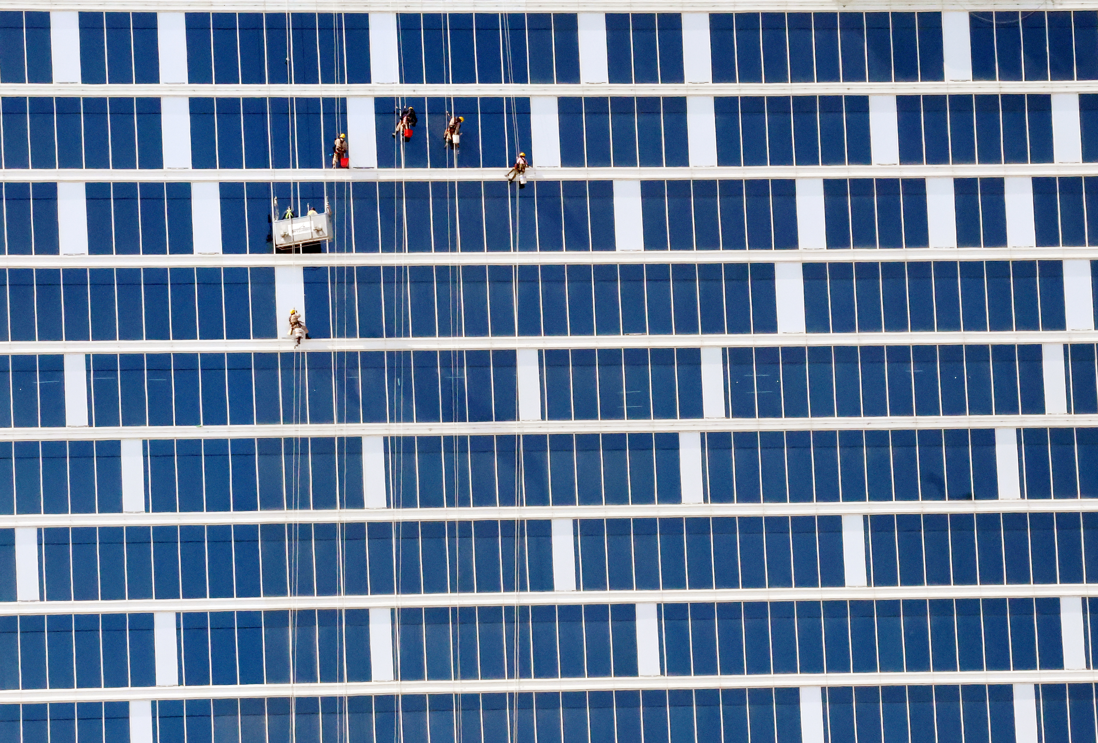 Workers clean the window panels of a building in Kuwait City on February 22, 2023.
