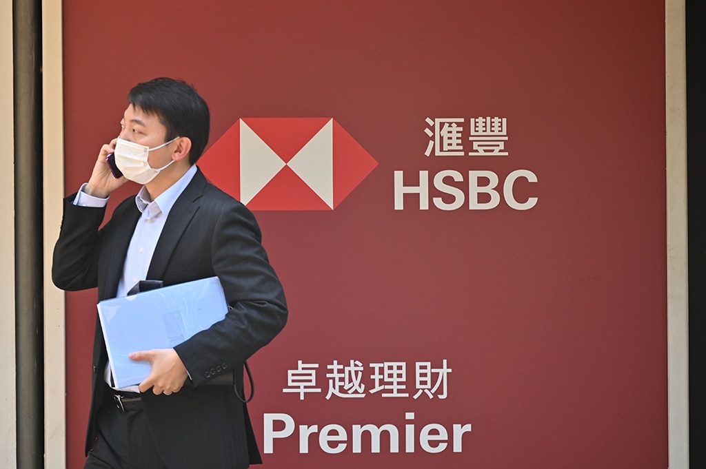 HONG KONG: A man uses his phone outside the headquarters of HSBC bank in Hong Kong on February 21, 2023. Banking giant HSBC on February 21 announced a dip in 2022 pre-tax profits last year, calling the ongoing impact of COVID-19 the main factor in its financial performance. - AFP