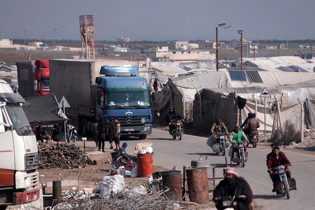 A convoy of trucks from Doctors Without Borders (MSF), carrying aid to earthquake victims, drives past tents sheltering survivors, after entering Syria from Turkey via the Al-Hamam border crossing in the countryside of Jindayris in northwestern Syria.- AFP