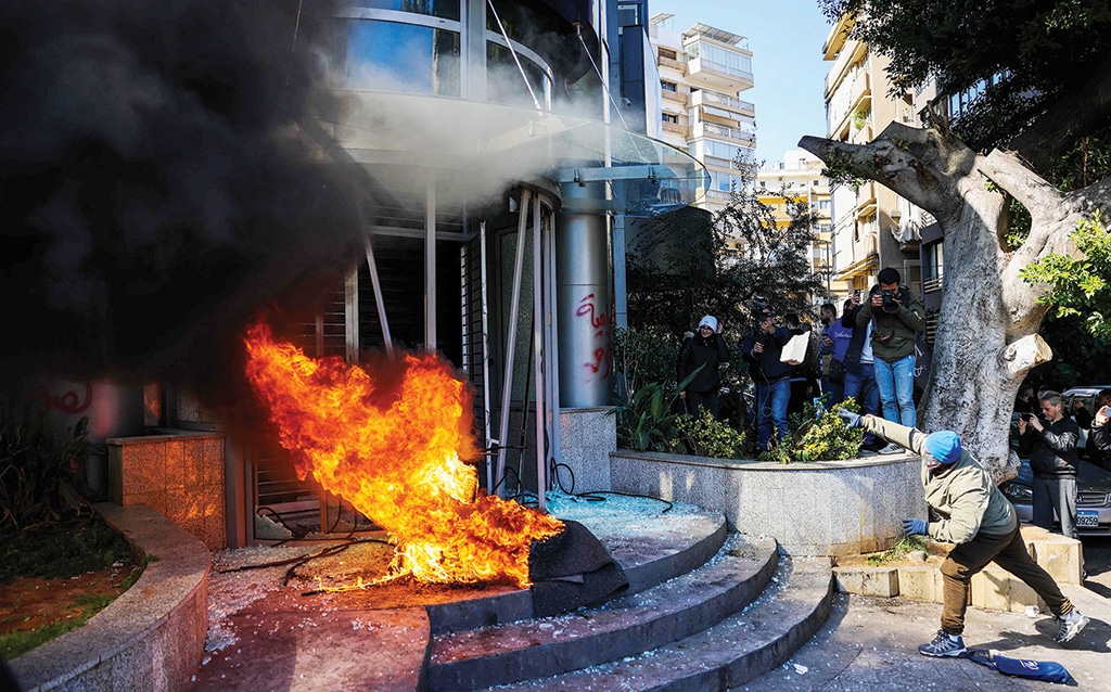 BEIRUT: A protester throws a brick at a bank after setting fire to tyres during a demonstration on Feb 16, 2023. — AFP