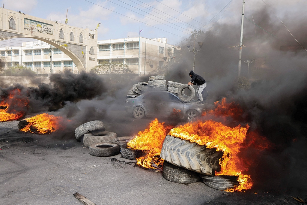 JERICHO: Palestinian protesters burn tyres to block a road leading into Jericho in the occupied West Bank on Feb 6, 2023 following a raid by Zionist forces. - AFP