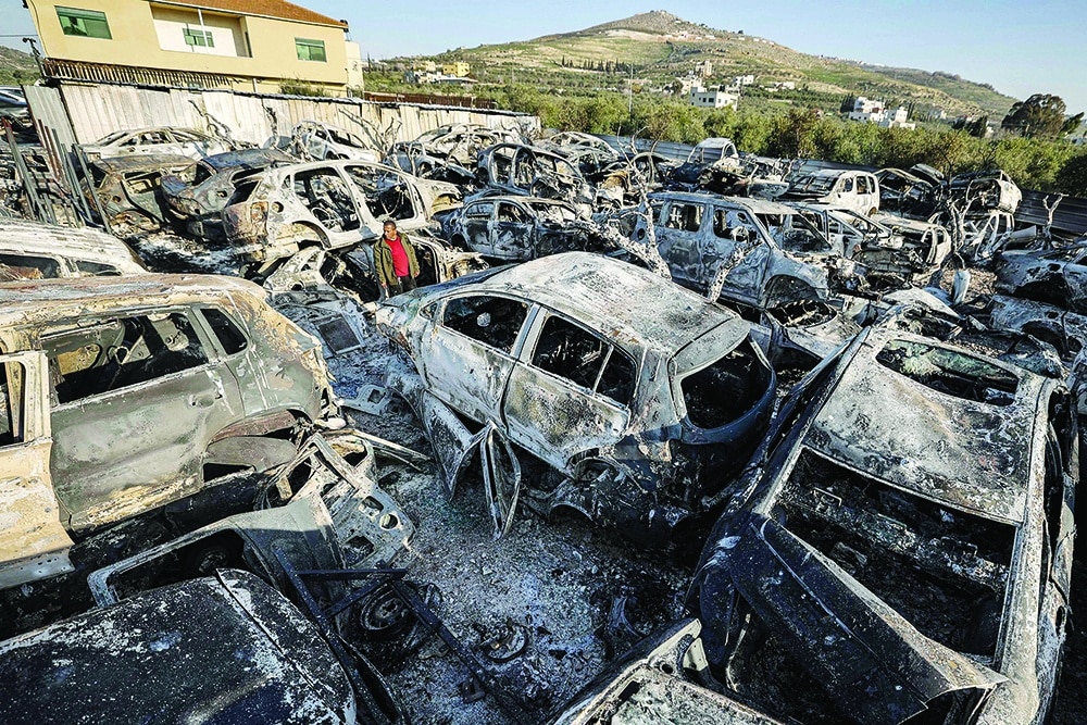 HUWARA: A man stands amidst destroyed cars in this town near Nablus in the occupied West Bank on Feb 27, 2023 after they were torched by Zionists overnight. — AFP