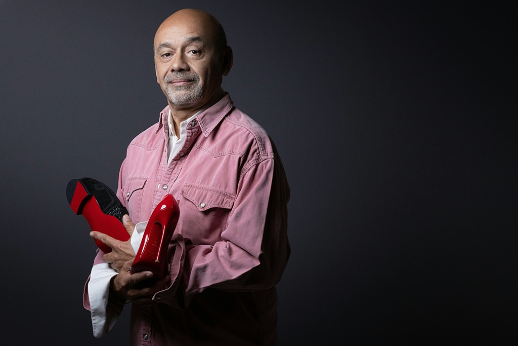 French shoe designer Christian Louboutin poses with two of his creations during a photo session in Paris.— AFP photos