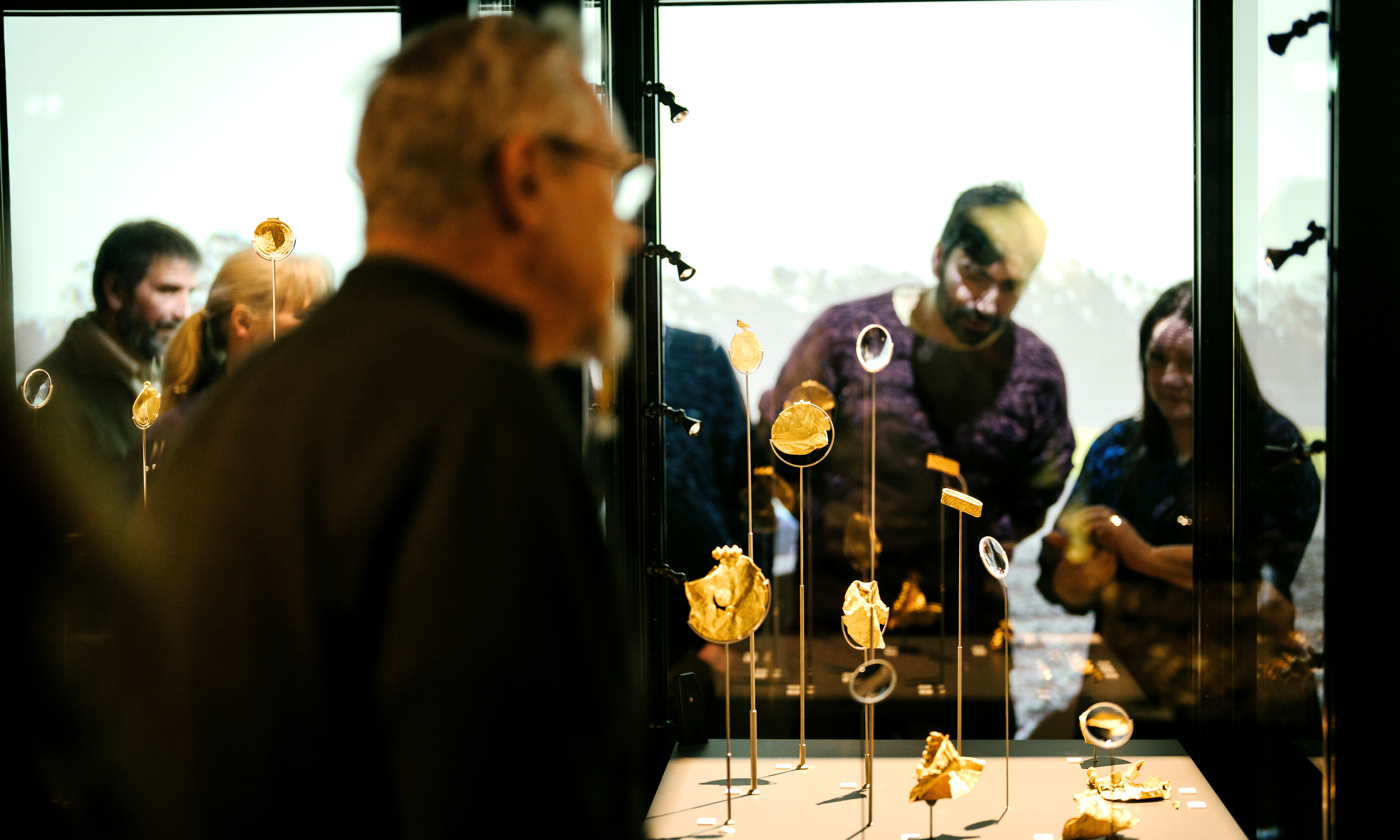 This handout pictures shows visitors looking at items found by treasure hunters in a Danish national museum exhibition.—AFP