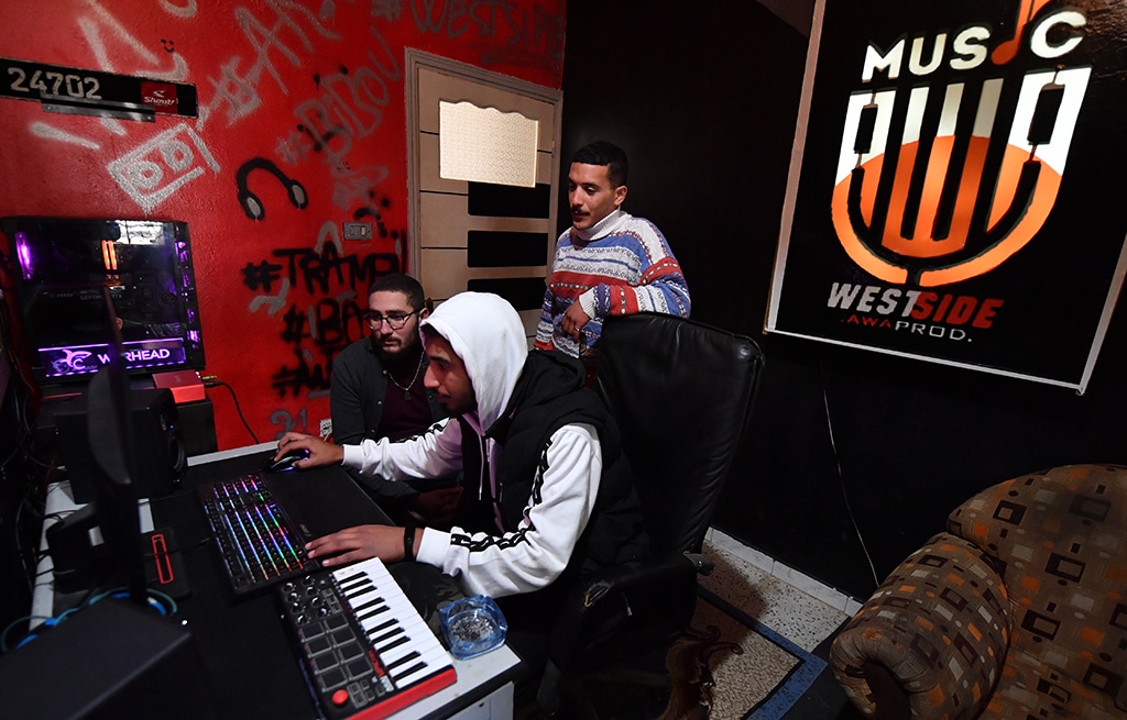 Mohamed Ali Ayari (center), a rapper from a down-at-heel Tunis district, stands at a recording studio in Douar Hicher.— AFP photos 