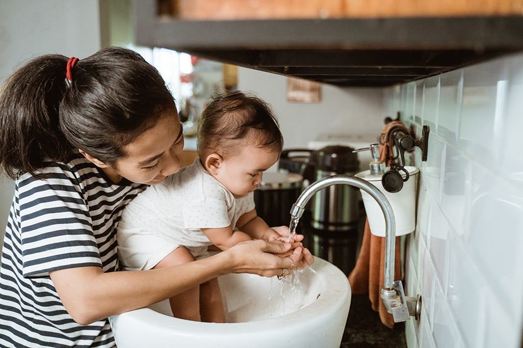 mother help her baby to wash hand in the sink