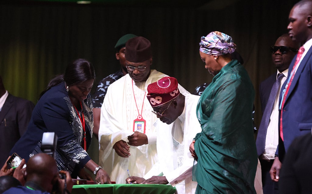 ABUJA: Nigeria’s President-elect Bola Tinubu (C) signs papers during the presentation of the certificate of return to the President-elect by the Independent National Electoral Commission (INEC) in Abuja. – AFP