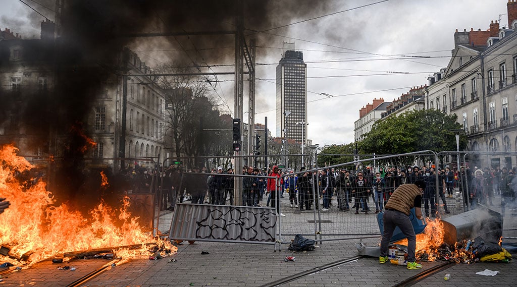 NANTES, France: A protestor feeds a burning barricade during a demonstration in Nantes, western France. - AFP