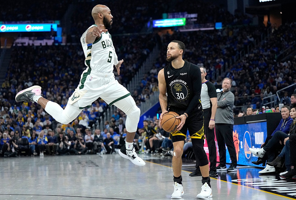 SAN FRANCISCO: Stephen Curry #30 of the Golden State Warriors pump fakes and watches Jevon Carter #5 of the Milwaukee Bucks leap past him in the air during the second quarter at Chase Center on March 11, 2023.- AFP