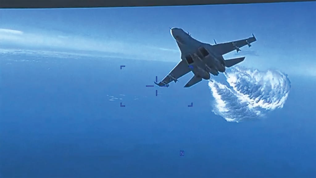 This handout image taken from video shows onboard footage from a US Air Force MQ-9 drone as it is approached the first time by a Russian SU-27 aircraft jettisoning fuel over the Black Sea on March 14, 2023. - AFP