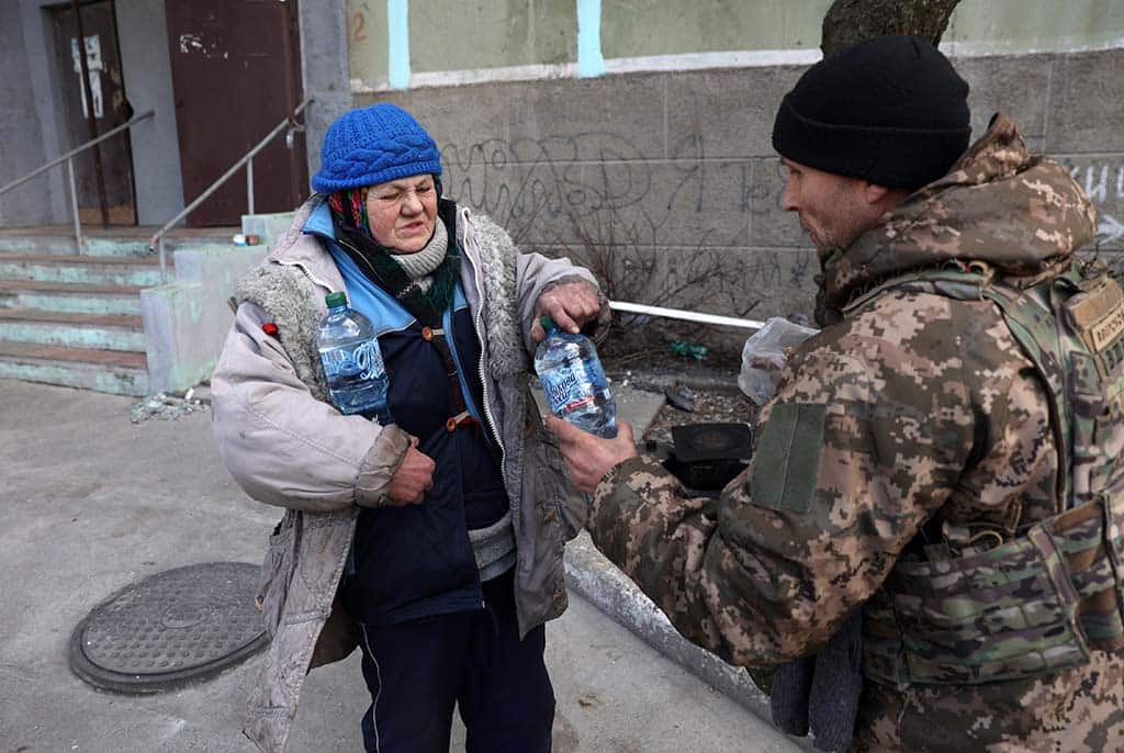 BAKHMUT, Ukraine: A Ukrainian serviceman gives food and water to a local elderly woman in the town of Bakhmut in the Donetsk region. - AFP