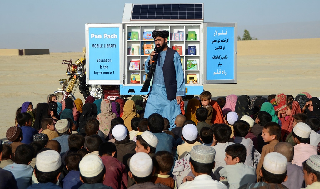 In this photograph taken on May 17, 2022, Matiullah Wesa, head of PenPath and advocate for girls' education in Afghanistan, speaks to children during a class next to his mobile library in Spin Boldak district of Kandahar Province. - Wesa, the founder of a project that campaigned for girls' education in Afghanistan, has been detained by Taliban authorities in Kabul, his brother and the United Nations said on March 28, 2023. (Photo by Sanaullah SEIAM / AFP)
