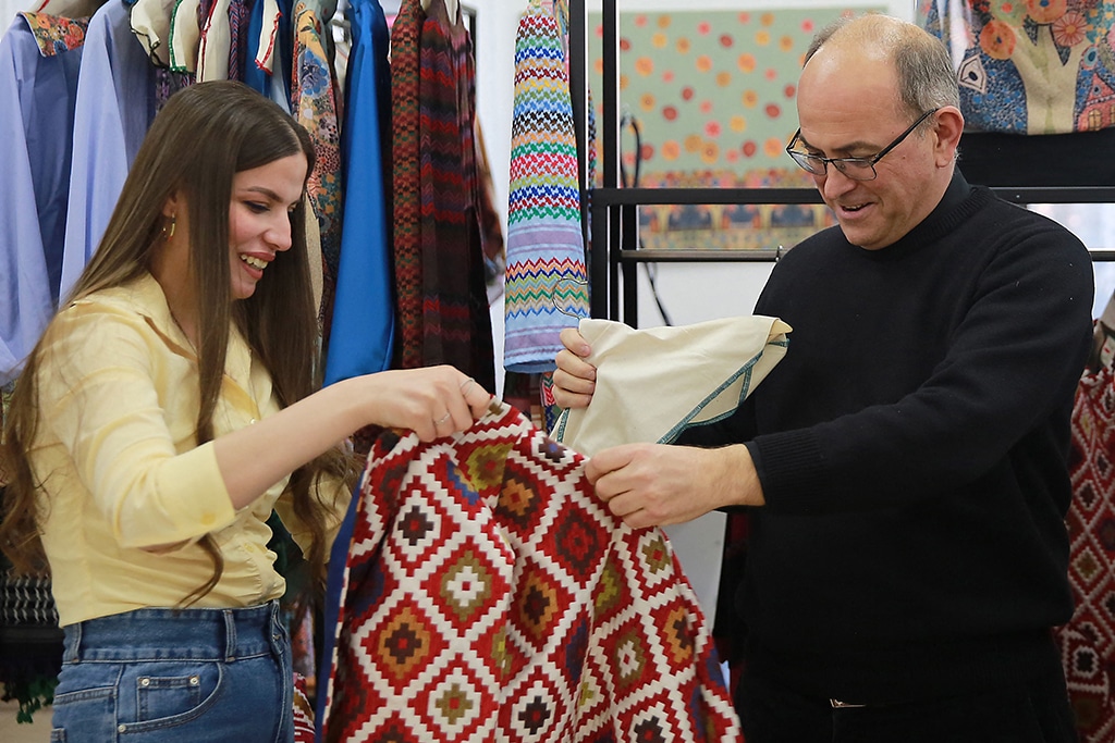 In this picture taken on March 12, 2023 in Amman, Italian priest Mario Cornioli and an Iraqi woman check an outfit at the atelier of ‘Rafedin’, a sewing project set up by Italians to help Iraqi refugee women in Jordan. — AFP photos
