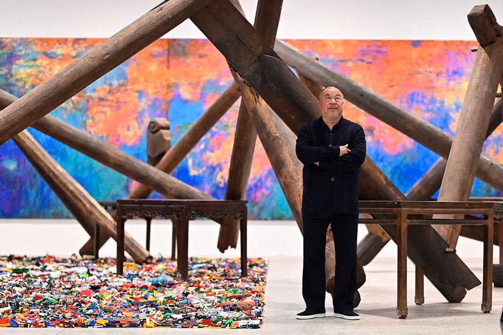 Chinese artist Ai Weiwei poses in front of his art pieces displayed during the press preview for the exhibition 'Ai Weiwei: making sense' at the Design Museum, in London.— AFP