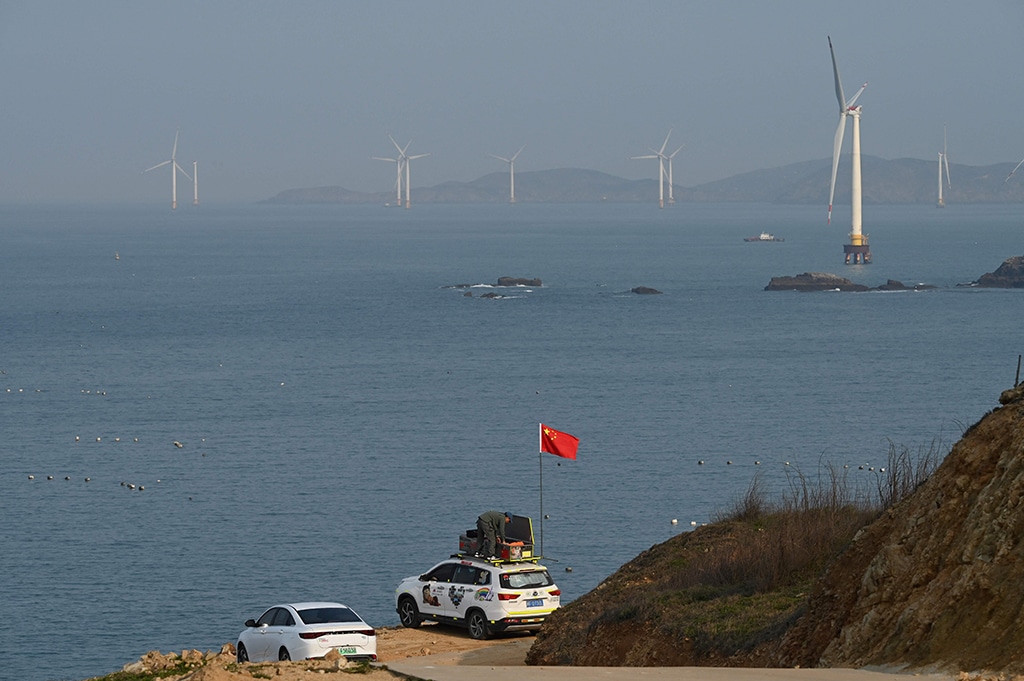 PINGTAN: A man sets up a Chinese flag on his car as he prepares to look at the view of the Taiwan Strait, towards the zone where China said it would conduct live fire exercises northeast of Pingtan island. – AFP