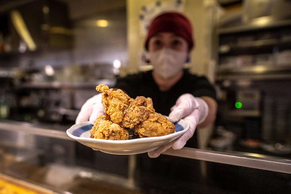 This picture shows Hiromi Matsumoto serving a plate of karaage, a Japanese style fried chicken at an izakaya bar in Tokyo. — AFP photos