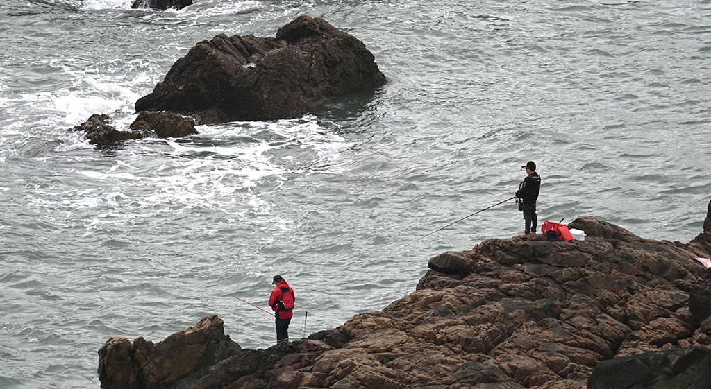 PINGTAN: Two men fish from rocks on Pingtan island, opposite Taiwan, in China’s southeast Fujian province. – AFP