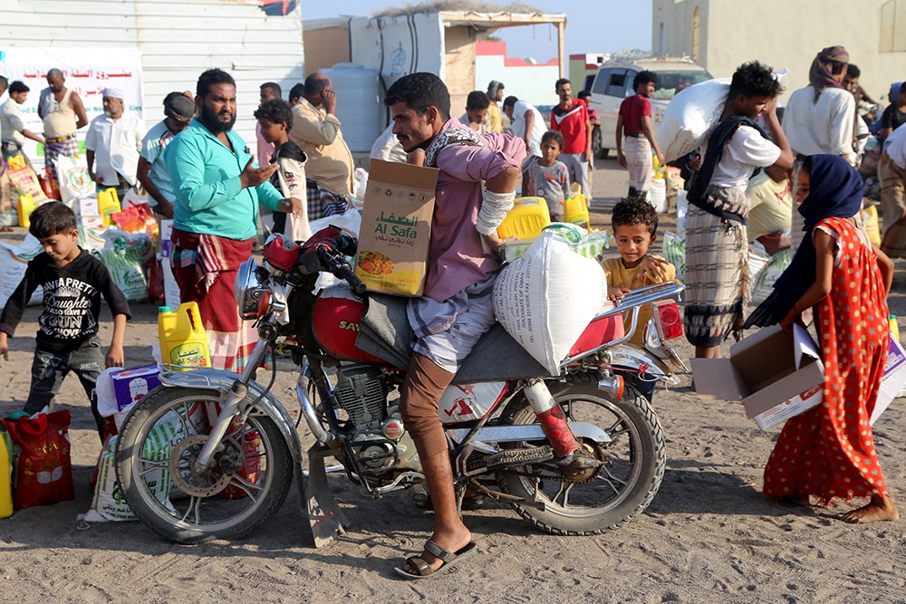 HODEIDAH: Displaced Yemenis receive sacks of food aid at a camp in Hays district in the war-ravaged western province of Hodeidah, on April 20, 2023. — AFP