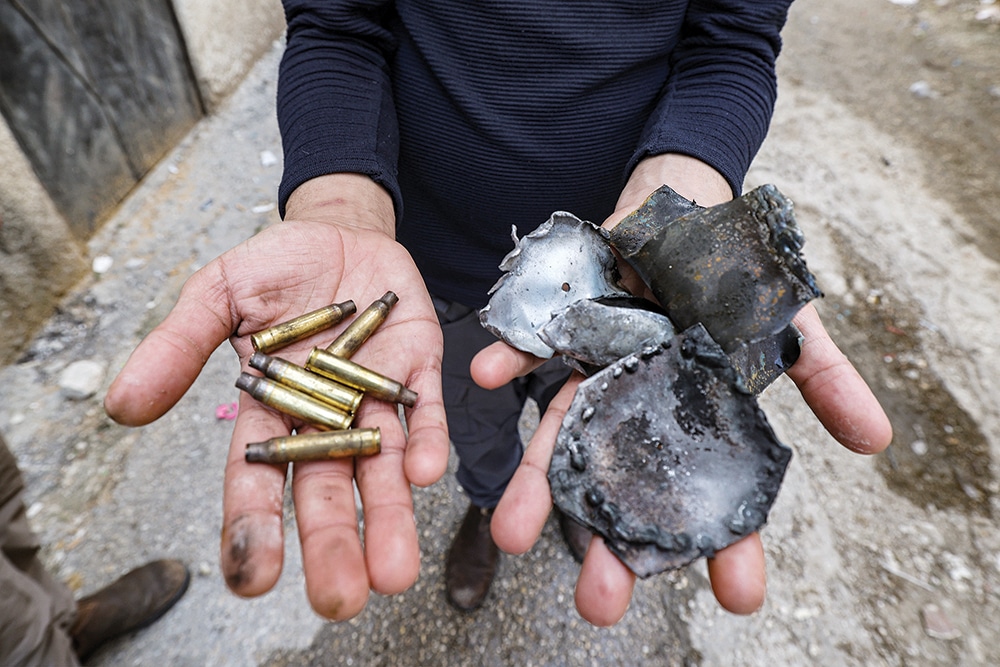 WEST BANK: A man holds bullet casings and shrapnel found following a Zionist military operation at the Jenin camp for Palestinian refugees in the occupied West Bank. — AFP
