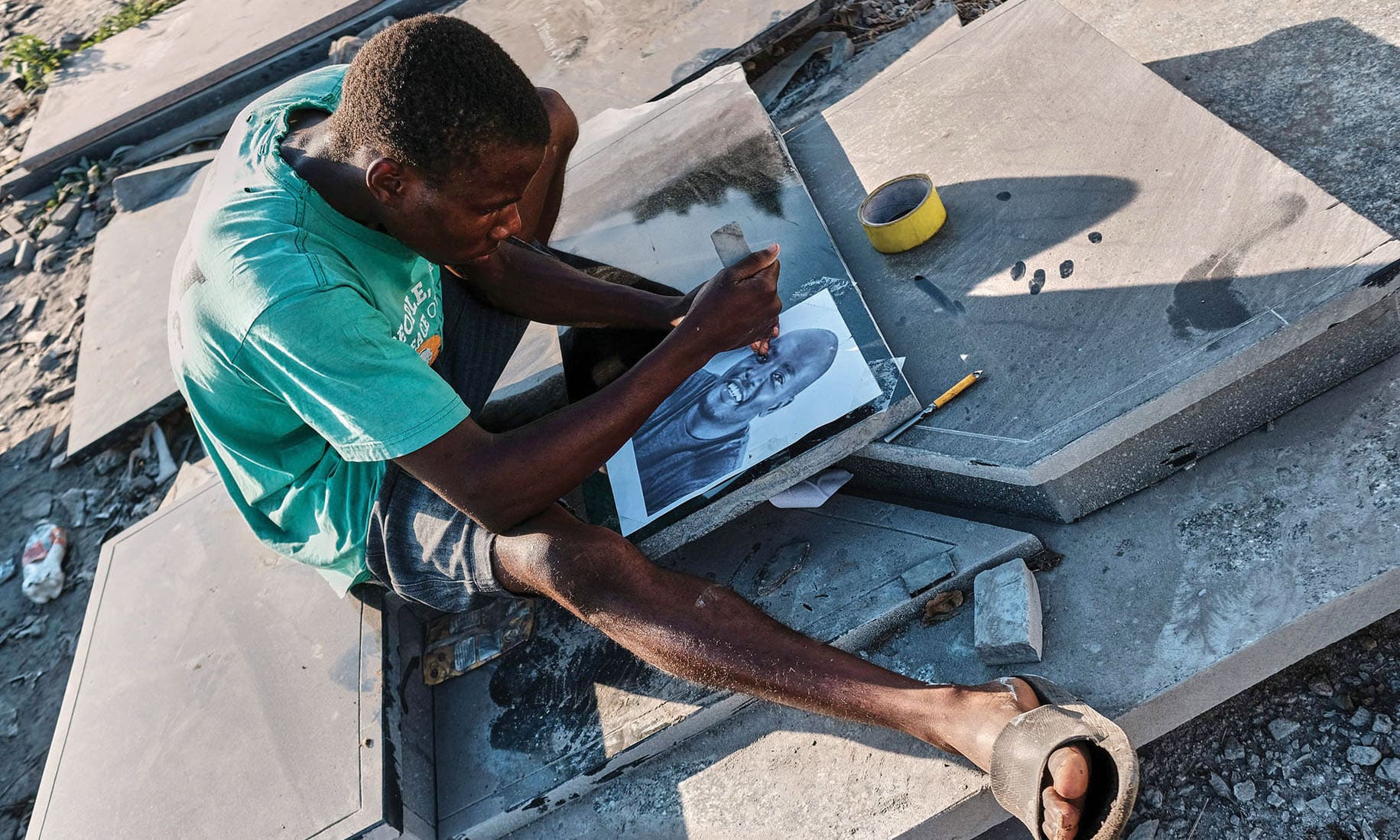 Denzel Karombe a 19-year-old school leaver who engraves portrait artworks onto polished black granite tombstones for Nyumba Yanga a tombstone-making business uses a drill bit and tapping stone to etch a potrait at his workstation in Rugare township Harare, Zimbabwe.—AFP photos
